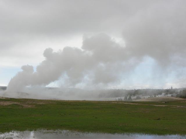 Old Faithful erupting looks different from the newer lodge. The wind is blowing really hard.