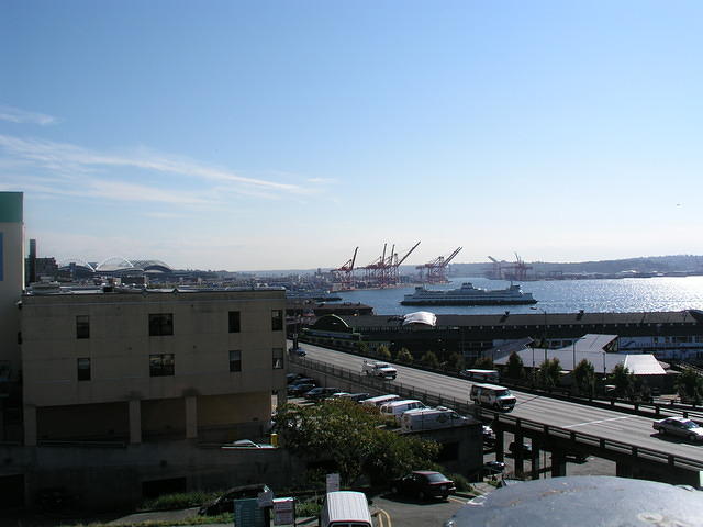 Looking to the sound and seeing some loading docks, a ferry and the sports stadiums.